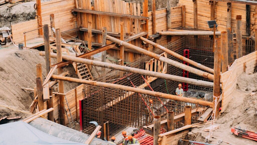 pexels photo 12032980 Aerial view of a construction site with workers, wooden framework, and scaffolding.
